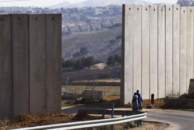 Palestinians walk near an opening in Israel's security fence in the east Jerusalem neighborhood of A-tur (photo credit: REUTERS)