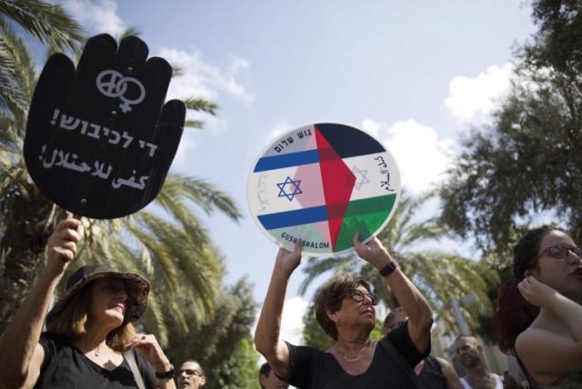 Left - wing protesters hold placards during a demonstration in Tel Aviv (photo credit: REUTERS)