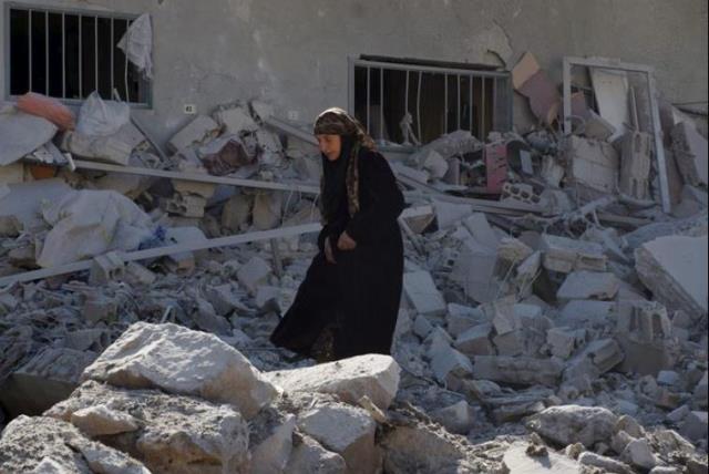 A woman makes her way through the rubble of damaged buildings after airstrikes by pro-Syrian government forces in the rebel held town of Dael, in Deraa Governorate, Syria February 12, 2016. (photo credit: REUTERS)