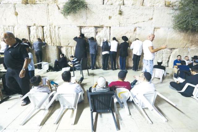 Worshippers sit on the ground on Tisha Be’av at the Western Wall, as a sign of mourning, in commemoration of the destruction of the Temple (photo credit: MARC ISRAEL SELLEM)