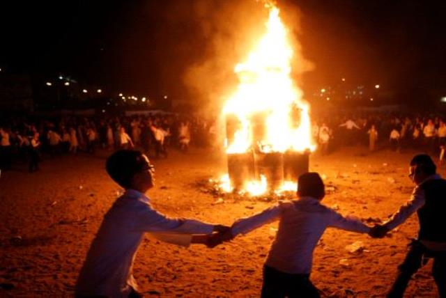 Ultra-Orthodox Jewish boys dance around a bonfire as they celebrate the Jewish holiday of Lag Ba'Omer in the city of Ashdod, Israel May 13, 2017 (photo credit: REUTERS)