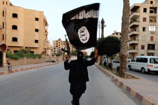 A MEMBER of ISIS waves the group’s flag in Raqqa (photo credit: REUTERS)